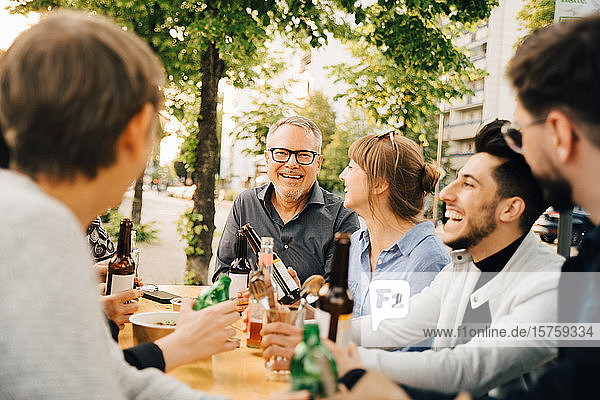 Porträt eines glücklichen reifen Mannes  der mit Freunden zusammensitzt und sich in geselliger Runde amüsiert