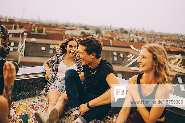 Fröhliche männliche und weibliche Freunde genießen auf der Terrasse während einer Dachparty