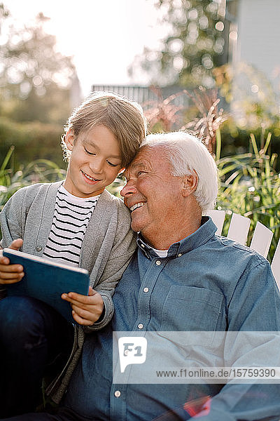 Smiling grandfather and grandson using digital tablet in backyard