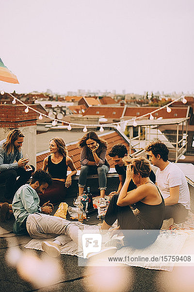 Männliche und weibliche Freunde genießen Dachparty auf der Terrasse in der Stadt