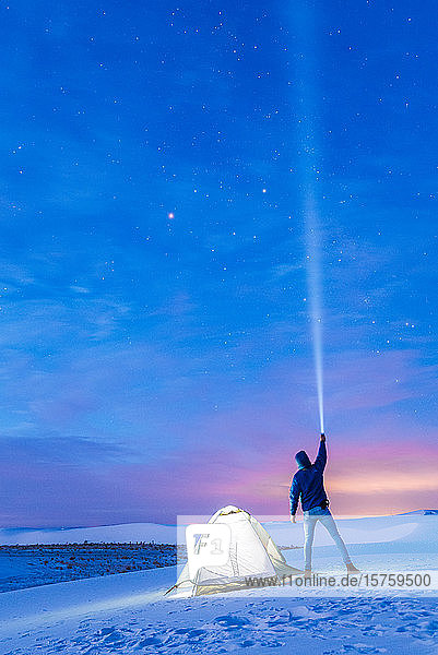 Man by tent shining torch into sky  White Sands National Monument  New Mexico  US