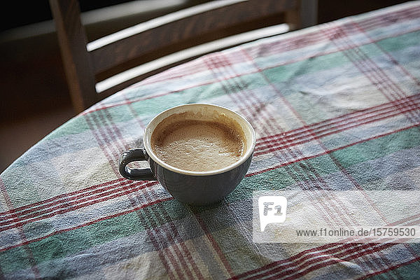 Tasse Kaffee auf mit kariertem Tuch bedecktem Tisch