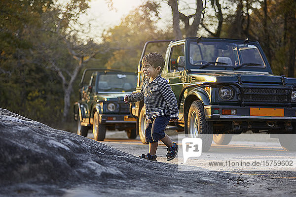 Kleiner Junge erkundet die Natur, Geländewagen im Hintergrund