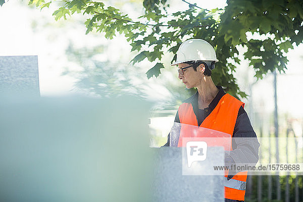 Woman working outdoors in a high vis jacket and safety hard hat.