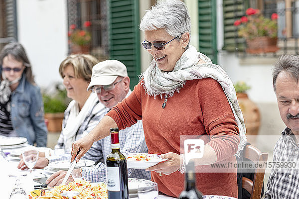 Frau serviert Pasta beim Familienessen im Garten  Florenz  Italien