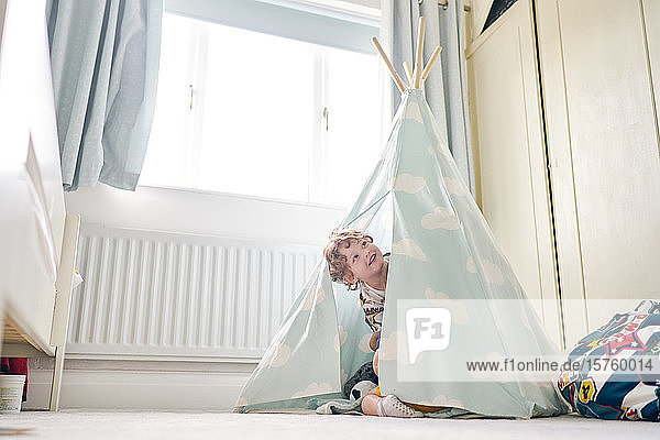 Toddler playing in teepee at home