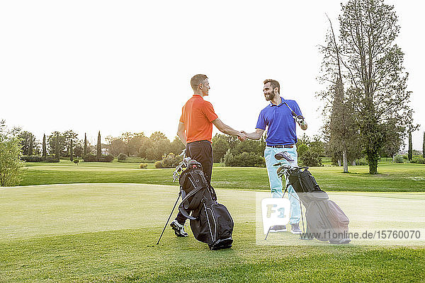 Freunde schütteln Hände auf dem Golfplatz