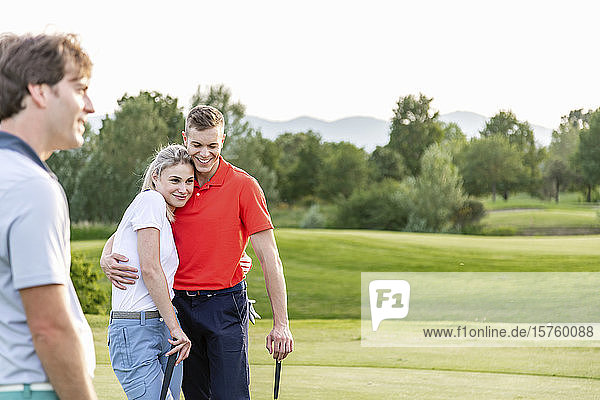 Mann und Paar umarmen sich auf dem Golfplatz