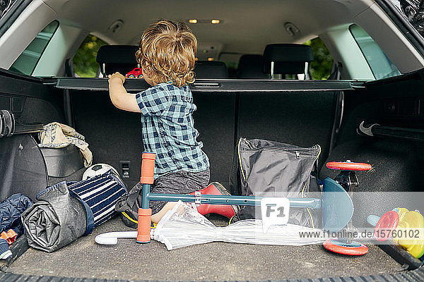 Toddler playing with toy car in back of vehicle