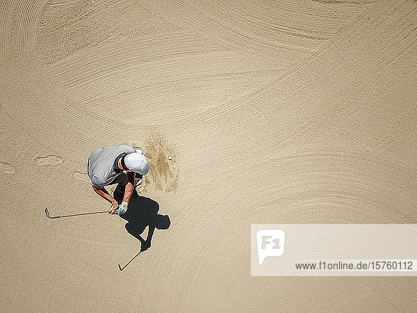 Mann spielt Golf im Bunker