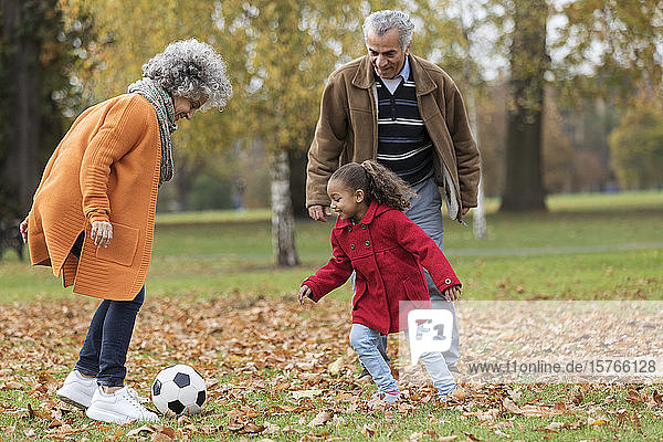 Großeltern spielen Fußball mit Enkelin im Herbst Park