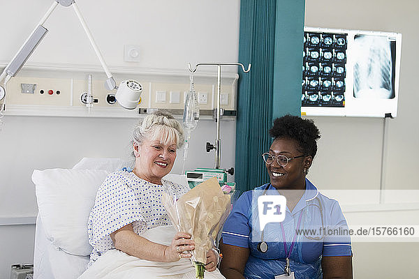Eine Patientin zeigt der Krankenschwester im Krankenhaus Blumen