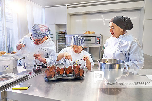 Koch hilft Schülern mit Down-Syndrom beim Backen von Muffins in der Küche