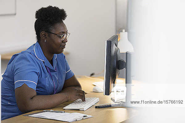 Weibliche Krankenschwester arbeitet am Computer in einer Arztpraxis