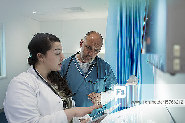 Doctors using digital tablet in hospital room