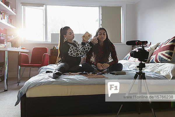 Teenager-Mädchen beim Vloggen  die auf dem Bett Make-up auftragen