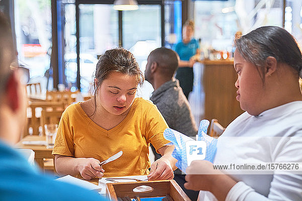 Junge Frauen mit Down-Syndrom reinigen Silberbesteck in einem Café