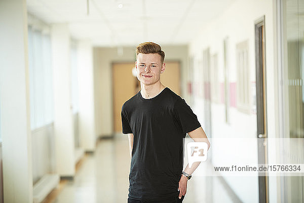 Portrait confident high school boy in corridor