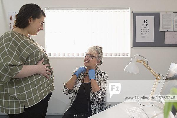 Ärztin untersucht schwangere Frau in Arztpraxis