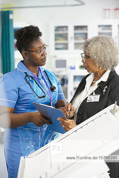 Ärztin und Krankenschwester mit Klemmbrett im Gespräch im Krankenhaus
