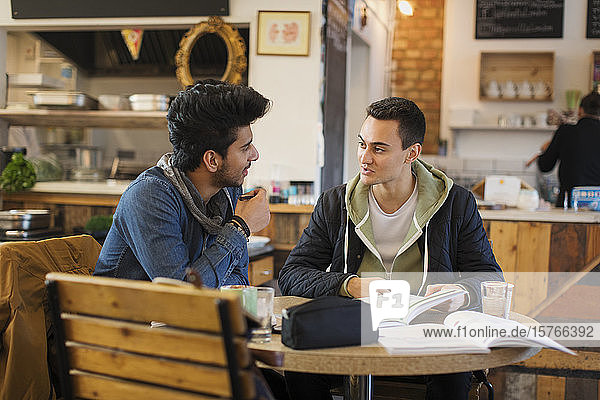 Junge männliche Studenten studieren und unterhalten sich in einem Café