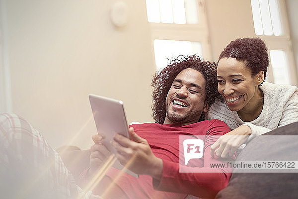 Glückliches Paar benutzt digitales Tablet auf dem Sofa