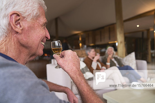 Glücklicher älterer Mann  der mit Freunden im Hotel ein Getränk trinkt