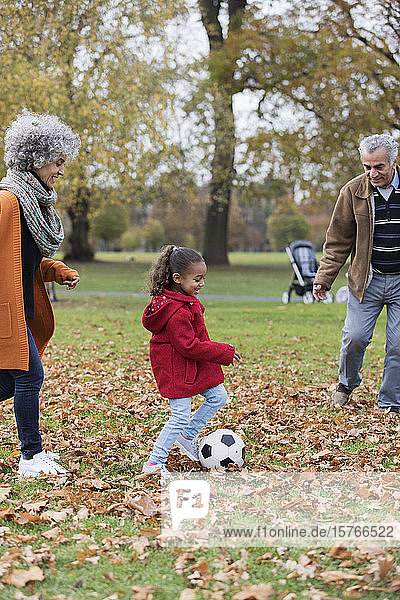 Großeltern spielen Fußball mit Enkelin im Herbst Park