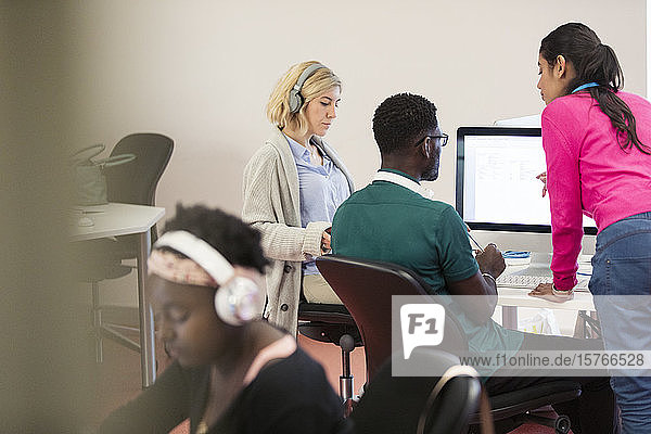 Ein Dozent der Volkshochschule hilft Studenten an den Computern im Computerlabor