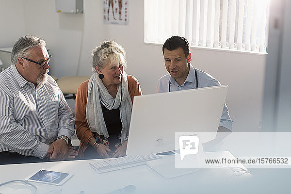 Arztgespräch mit einem älteren Ehepaar am Computer in einer Arztpraxis