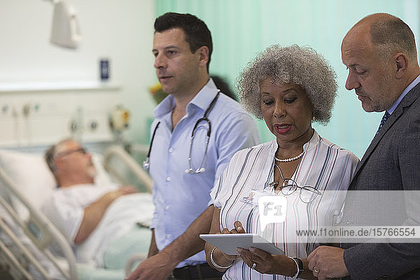 Ärzte mit digitalem Tablet bei der Visite  Beratung im Krankenhauszimmer
