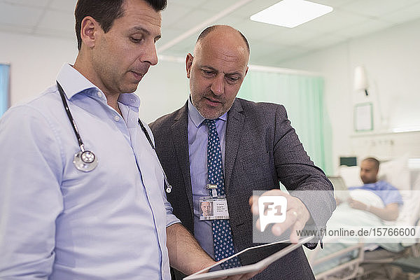 Male doctors with digital tablet making rounds  consulting in hospital room