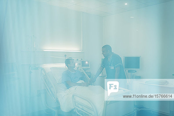 Krankenpfleger im Gespräch mit einem Patienten im Krankenhauszimmer