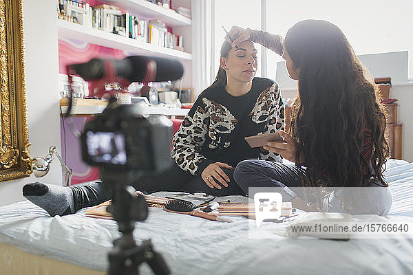 Teenager-Freundinnen führen einen Vlog über das Auftragen von Make-up im Bett