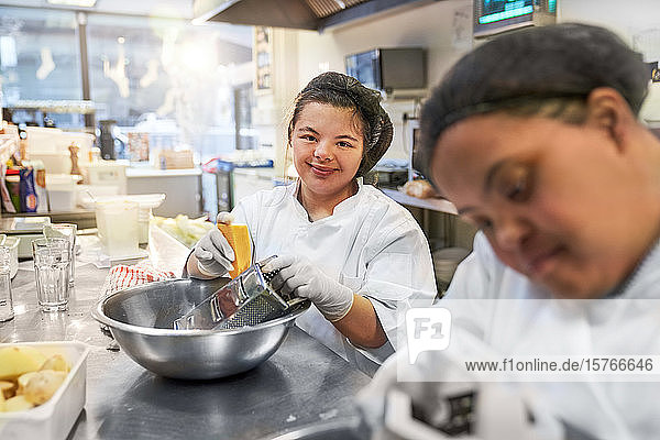 Porträt einer selbstbewussten jungen Frau mit Down-Syndrom  die in einem Cafe kocht