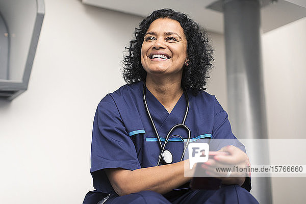 Porträt einer lächelnden  glücklichen Ärztin  die ein Smartphone benutzt