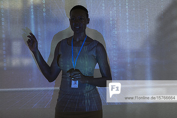 Geschäftsfrau  die eine Besprechung vor einer Projektionsfläche mit binärem Code leitet