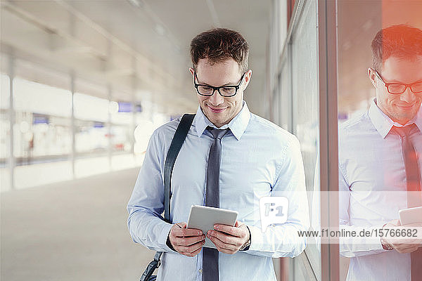 Businessman using digital tablet in train station