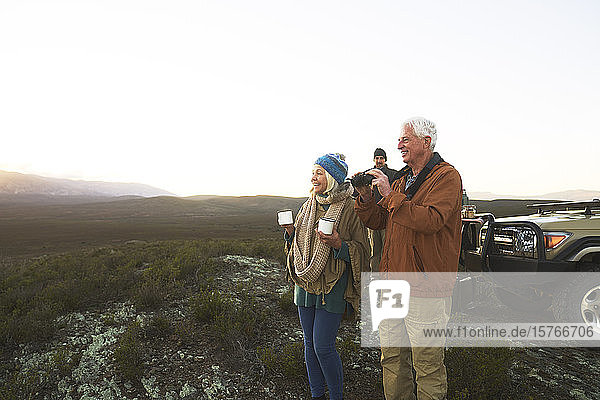 Älteres Paar auf Safari  das ein Fernglas benutzt und Tee trinkt