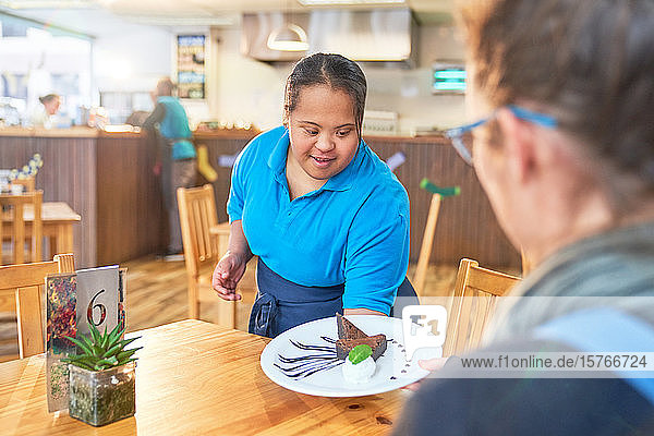 Junge Frau mit Down-Syndrom serviert Dessert in einem Cafe