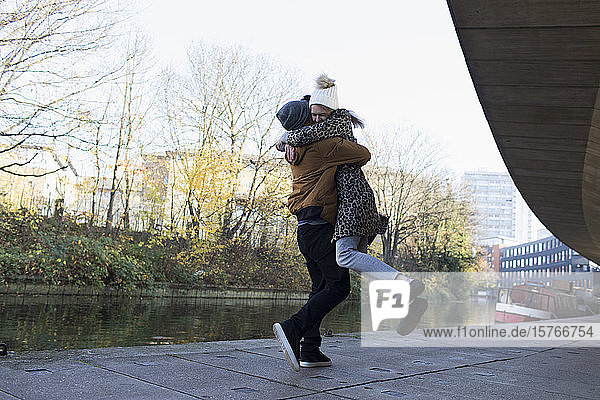 Glückliches junges Paar  das sich entlang eines städtischen Kanals umarmt
