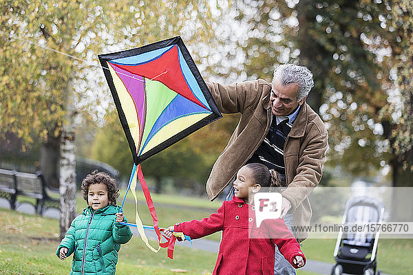 Grandfather and grandchildren flying a kite in autumn park