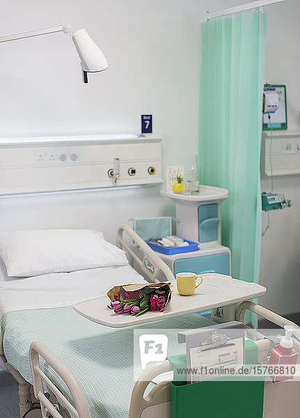 Flowers on tray over hospital bed in vacant hospital room