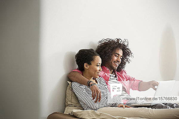 Glückliches  zärtliches Paar mit Laptop auf dem Bett
