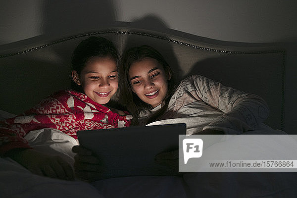 Mädchen schauen einen Film auf einem digitalen Tablet in einem dunklen Schlafzimmer