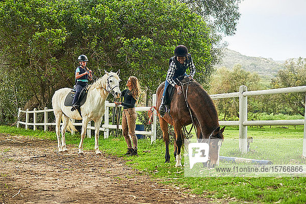 Girls preparing for horseback riding lesson at rural paddock