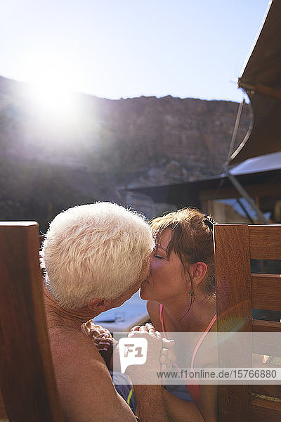 Glückliches romantisches älteres Paar  das sich auf einem sonnigen Balkon küsst
