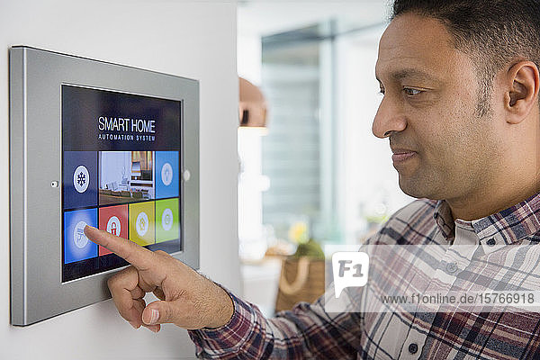 Mann stellt den Alarm des intelligenten Heim-Navigationssystems am Touchscreen ein