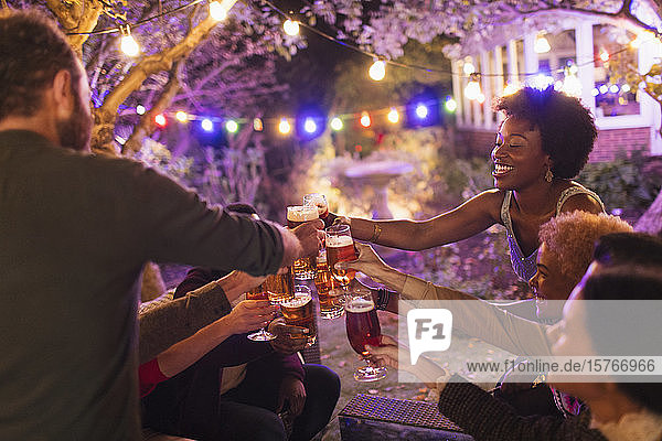 Fröhliche Freunde stoßen bei einer Gartenparty mit Biergläsern an