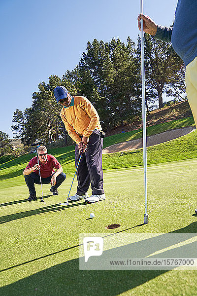 Männlicher Golfer beim Putten auf einem sonnigen Golfplatz